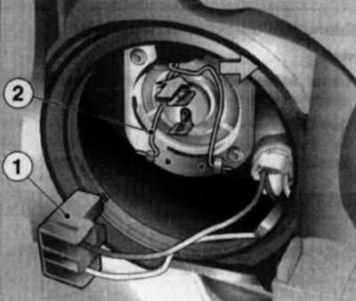 12.8. Odłączyć złącze przewodów elektrycznych (1) i nacisnąć uchwyt mocujący (2) w kierunkach…