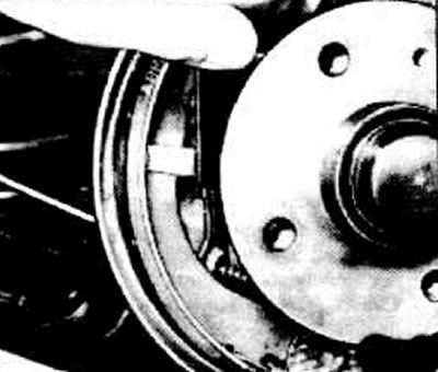 Insert the handbrake cable into the brake shield and attach it to the brake shoes.