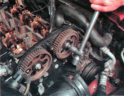 7. Holding the camshaft from turning with a 24 mm wrench, use a TORX E14 wrench to unscrew the bolt…