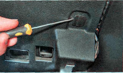 6. Using a slotted screwdriver, remove the retainer from the lower trim of the instrument panel.